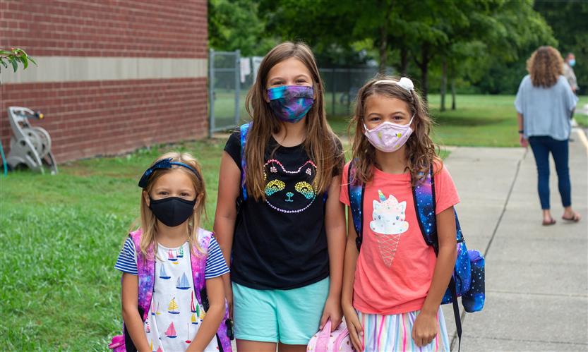 Three students smile while wearing masks